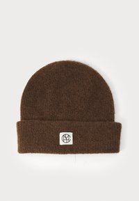 Bonnet en laine marron avec un revers, présentant une boîte blanche avec un logo noir. Texture douce, forme arrondie au sommet.