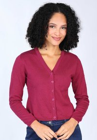 Burgunderfarbener gerippter Cardigan mit V-Ausschnitt, langen Ärmeln, gepunkteter Textur und vorderen Knöpfen. Tragen über dunklen Jeans.