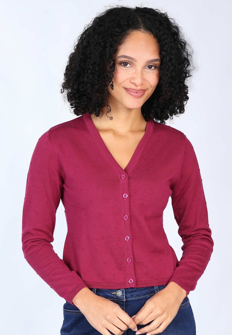 Burgunderfarbener gerippter Cardigan mit V-Ausschnitt, langen Ärmeln, gepunkteter Textur und vorderen Knöpfen. Tragen über dunklen Jeans.