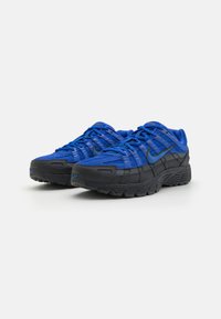 Blue and black sneakers featuring a mesh and suede upper, rounded toe, textured sole, and prominent branding on the side.