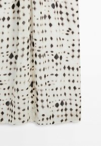 White fabric with black geometric irregular dot pattern, featuring diamond and oval shapes, hanging with soft folds.