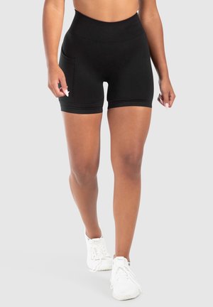 Zwarte high-waisted shorts met een soepele textuur, voorzien van een zijzak en een getailleerd ontwerp, gedragen met witte sportschoenen.
