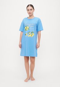 Robe t-shirt in cotone azzurro chiaro con maniche corte, caratterizzata da una stampa grafica di limoni gialli e testo sul davanti. Fit rilassato, lunghezza a ginocchio.