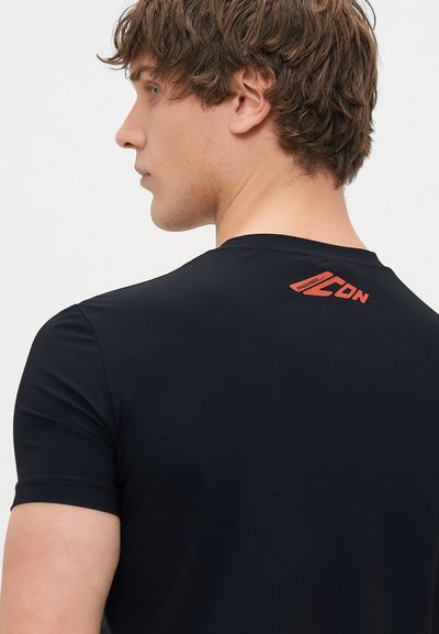 Camicetta nera attillata a maniche corte con una texture liscia; presenta un logo rosso sul retro vicino al colletto.