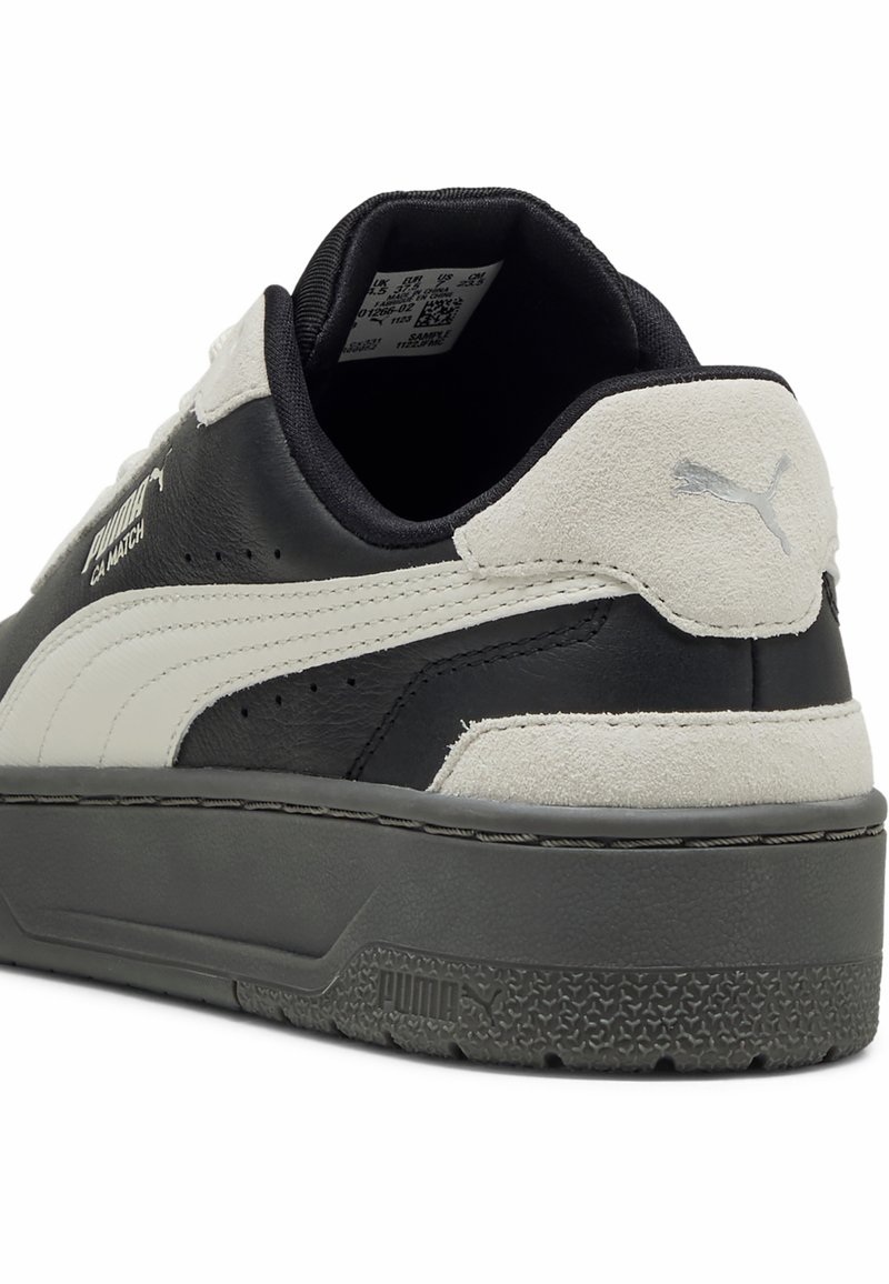 Czarno-białe sneakersy wykonane z materiałów skórzanych i zamszowych, z grubą szaro-skalą podeszwą oraz akcentami logo Puma po bokach i na pięcie.
