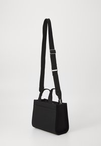 Black canvas handbag with a rectangular shape, featuring two top handles and an adjustable shoulder strap with metal hardware.