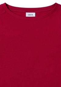Czerwona koszulka z okrągłym dekoltem, z hafrowanym wykończeniem dekoltu i białą metką z napisem "CECIL" wszytą w tylną część kołnierza.