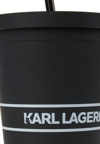 Vaso reutilizable negro con acabado mate, que presenta una franja horizontal blanca y el logotipo de "KARL LAGERFELD" exhibido de manera prominente.