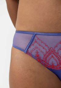 Slip in rete viola con ricami floreali rossi lungo il lato, dotato di una cintura liscia e una texture semi-trasparente.