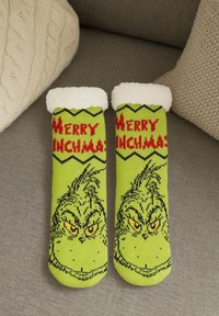 Calze di Natale verdi brillanti con polsini in pelliccia bianca, decorate con il volto del Grinch e la scritta "Merry Grinchmas" in lettere rosse.