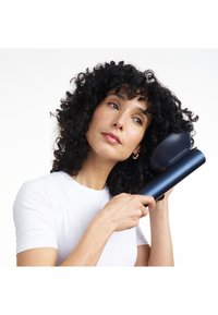 Asciugacapelli cordless con corpo elegante di colore blu navy. Presenta un ugello arrotondato e una presa ergonomica, adatta per modellare capelli ricci.