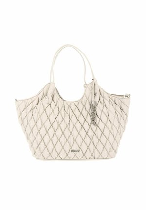 Sac à main matelassé beige DKNY avec double poignée et un petit pendentif logo en métal suspendu à une poignée.