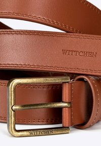 Bruine leren riem met een metalen bronzen gesp. Kenmerkt zichtbare stiksels en een geperst logo "WITTCHEN" op de riem en de gesp.