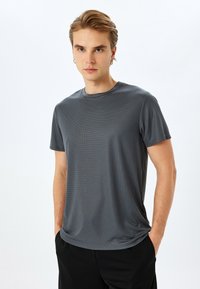 Grijs ribbelshortsleeve t-shirt met ronde hals, met een zachte textuur en een losse pasvorm, gecombineerd met zwarte broek.