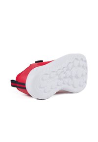 Zapatilla de piel roja con una superficie texturizada y suela de goma blanca. Presenta una lengüeta de tirón a rayas negras y rojas en el talón.