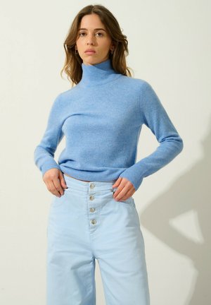 Lichtblauwe turtleneck trui van zacht materiaal, met lange mouwen en een getailleerd ontwerp, gedragen met lichtblauwe high-waisted broek met knopen.