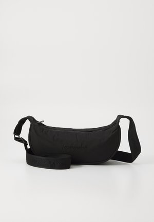 Fekete deréktáska puha anyagból, ívelt formával, állítható pánttal és dombornyomott logóval az elején. Simább textúra és minimalista dizájn.