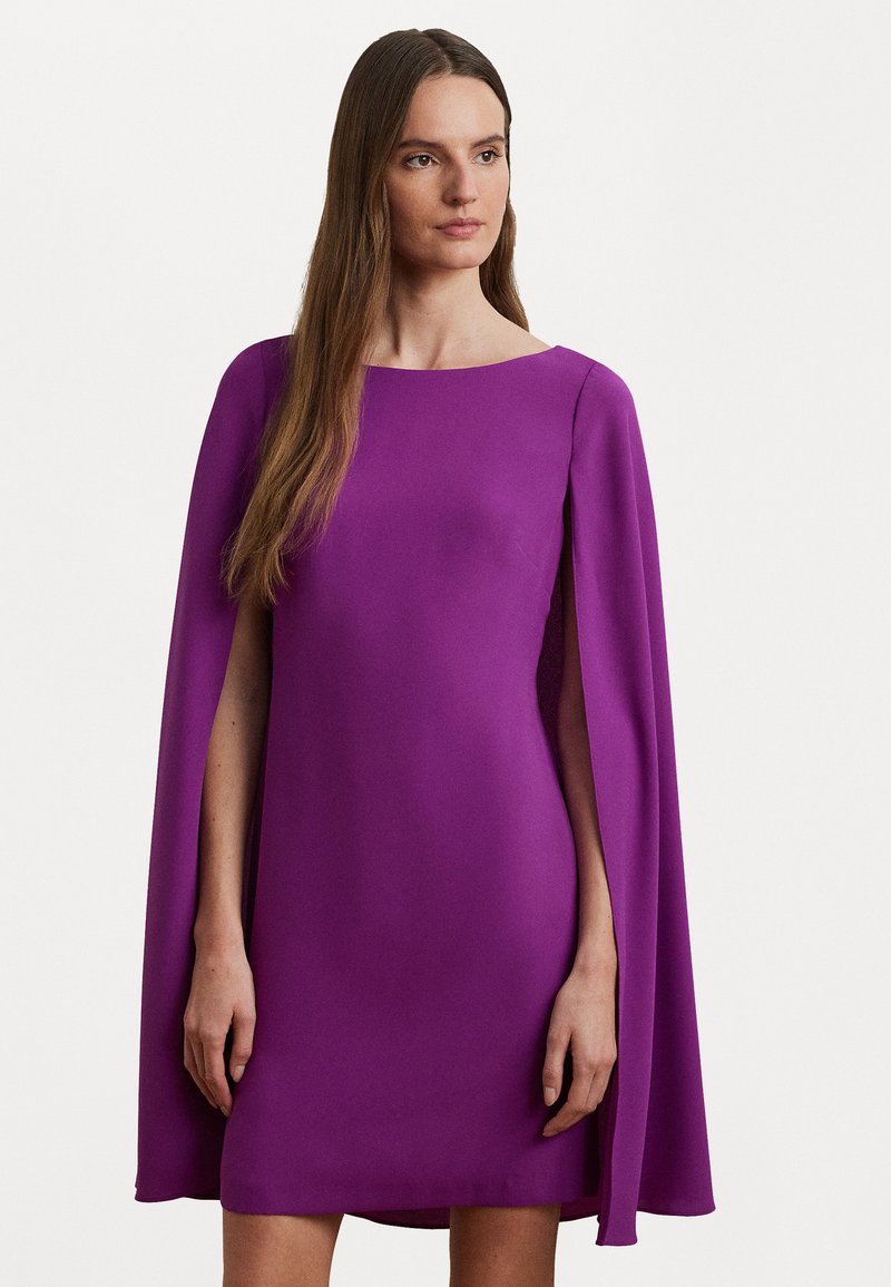 Violetti mekko, jossa on sileä pinta, leveä kaula-aukko ja valuva viittamainen hihoitus. Yksinkertainen malli, joka päättyy polven ylle.