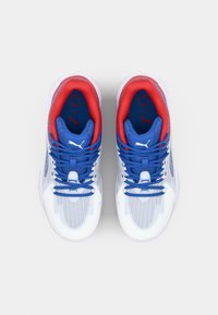 Sportschoenen met een witte mesh bovenkant, blauwe veters en rode accenten. Beschikt over een gestructureerde zool en een prominent logo op de tong.