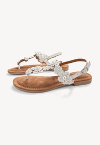 Sandali con accenti di fiori bianchi, suola piatta e soletta in suede color beige, con cinturino alla caviglia regolabile. Presentano motivi floreali con dettagli di perle.