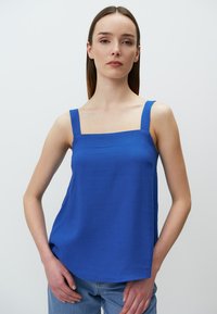 Koninklijkblauwe mouwloze top met vierkante halslijn, platte schouderbanden en een ontspannen pasvorm. Gladde stoftextuur, minimaal ontwerp zonder zichtbare patronen.