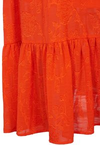 Tissu orange vif avec un étage froncé et un motif de broderie florale en relief, montrant une texture légère et semi-transparente.