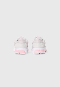 Baskets de sport blanches et roses avec des détails en mesh et géométriques, vues de l'arrière sur un fond blanc uni.