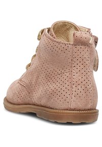 Růžové semišové kotníkové boty s perforovanou texturou, kulatou špičkou a zlatými krajkami. Nízká gumová podešev a malá ozdobná mašle na zadní straně.