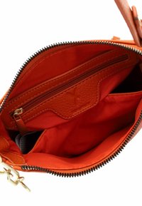Interieur van een oranje leren handtas met een ritsvak, een ruime compartiment en een soepele textielvoering. Gedetailleerd met gouden hardware.