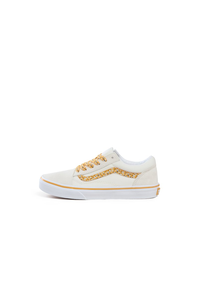 Sneakers en suédine blanche avec un motif floral doré sur le côté, semelle blanche et œillets dorés ; lacets plats pour un maintien sécurisé.