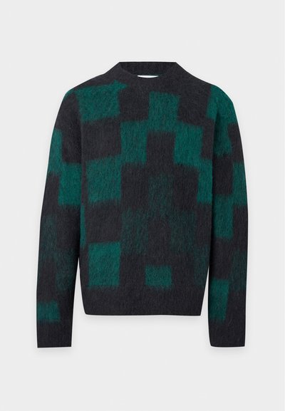 Pull noir et vert foncé duveteux avec un motif géométrique en blocs et des manches longues sur un fond clair uni.