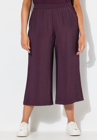 Fialové culottes kalhoty s elastickým pasem, texturovanou tkaninou a širokým střihem, doplněné bílými teniskami.