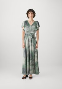 Maxi suknelė iš plaukiančios, lengvos medžiagos su žaliu ir pilku tye-dye raštu. V-žirklė, trumpi skristi rankoviai ir surištas liemuo.