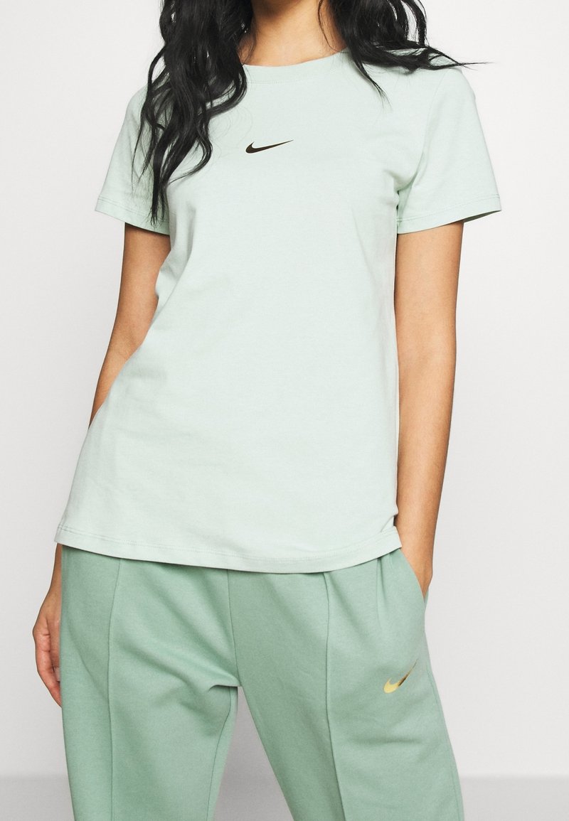 Ljusgrön bomulls T-shirt med rund halsringning och korta ärmar, prydd med en svart Nike-logga centralt på bröstet, tillsammans med matchande byxor.