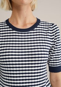 Top de mangas cortas a rayas en azul marino y blanco con un cuello redondo. La textura de punto presenta un patrón repetitivo de rayas alternas.