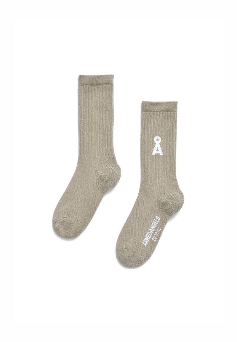 Beige, gerippte Socken aus weichem Material mit einem weißen Logo und Text in der Nähe des Knöchels. Das Design ist einfach und funktional.