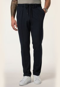 Marineblaue Jogginghosen mit elastischem Bündchen, Kordelzug, Taschen und schmal zulaufenden Beinen. Kombiniert mit weißen Sneakers für einen lässigen Look.