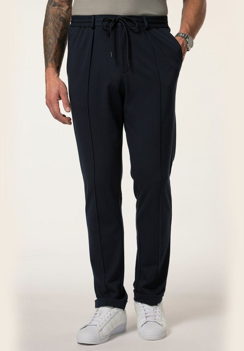 Marineblaue Jogginghosen mit elastischem Bündchen, Kordelzug, Taschen und schmal zulaufenden Beinen. Kombiniert mit weißen Sneakers für einen lässigen Look.