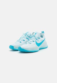 Light blue sports shoes with a textured upper, featuring a prominent blue Nike swoosh, flat laces, and a durable rubber sole.