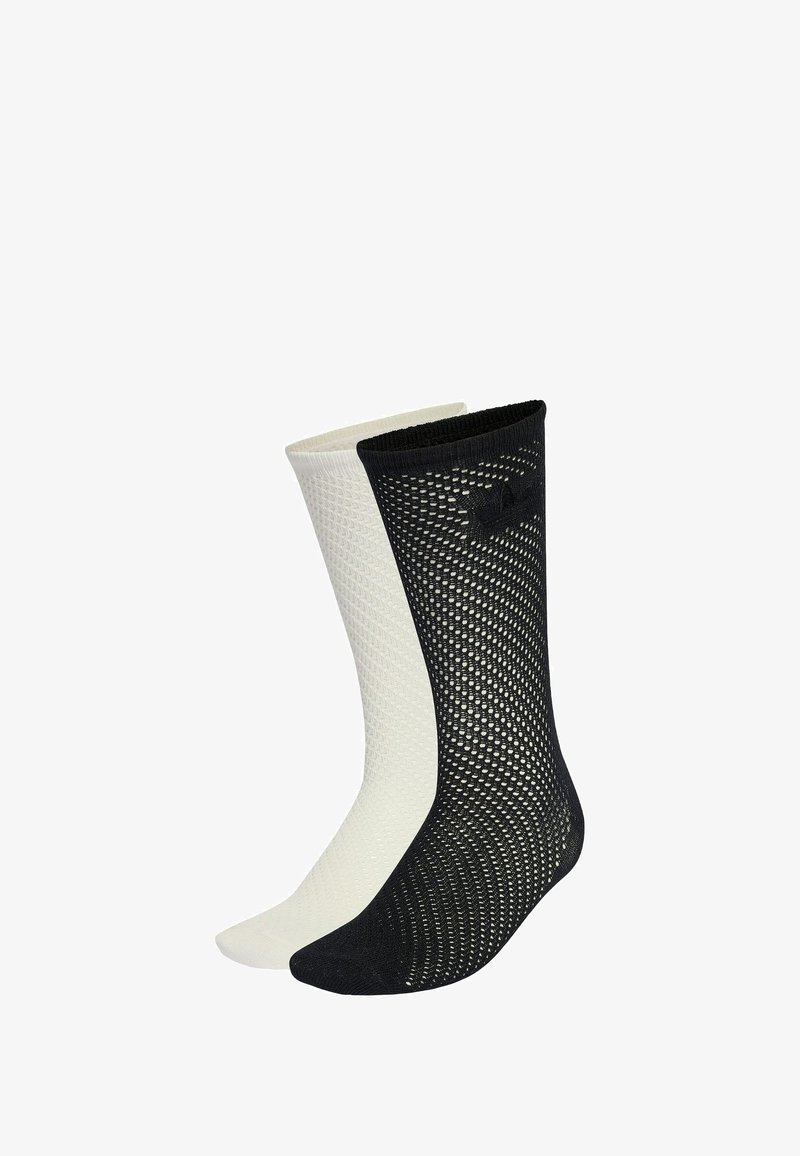 Pár ponožiek s sieťovaným vzorom, jedna čierna a jedna biela, zobrazené vedľa seba na bielom pozadí.