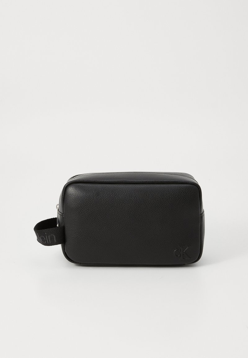 Necessaire de couro preto em formato retangular, com superfície texturizada, fecho por zíper e uma alça lateral com um detalhe do logotipo.