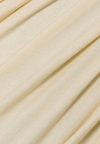 Zachte, beige stof met een geribbelde textuur, met subtiele plooien en een lichte uitstraling. Ideaal voor kledingstukken of meubelbekleding.