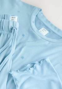 Ensemble haut à manches longues bleu doux et pantalon assorti avec une taille élastique et de petits motifs d'étoiles sur le tissu.