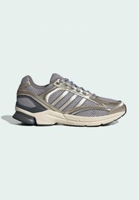Gray athletic shoe with a mesh upper, metallic accents, and a thick, cushioned sole. Features lacing and three stripe design on the sides.