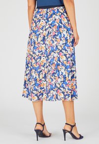 Falda midi floral con base azul, que presenta un patrón de formas abstractas en naranja, rosa y blanco. Cintura elástica, tela fluida.