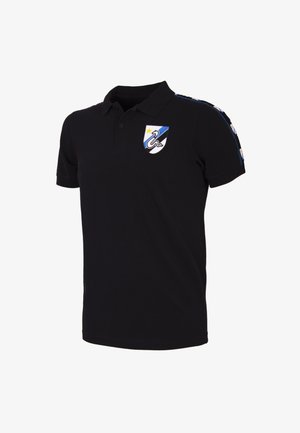 Zwarte polo met korte mouwen, voorzien van een geborduurd schildlogo in blauw en wit, en blauwe strepen langs de schouders.