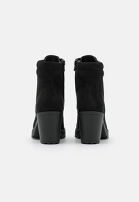 Stivaletti neri in suede, con tacco a blocco, dotati di un bordo avvolgente e cerniere laterali per un facile accesso. Superficie testurizzata e suola resistente.