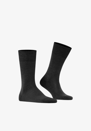 Pair of plain black mid-calf socks, one standing upright and the other angled to show heel and toe details on a white background.
