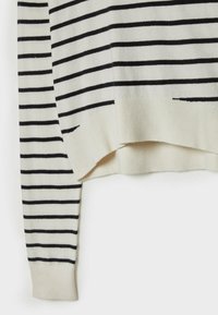 Pull en maille blanc à manches longues avec des rayures noires horizontales, doté de poignets et d'un ourlet côtelés, légèrement incurvé en bas.