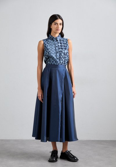 Navy blue dress featuring a sleeveless top with patterned fabric and a long, flowing skirt. Worn with black lace-up shoes.